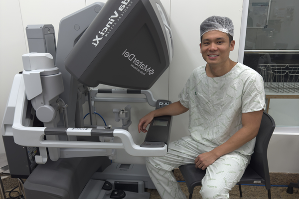 Dr. André Fujioka ao lado da plataforma cirúrgica robótica